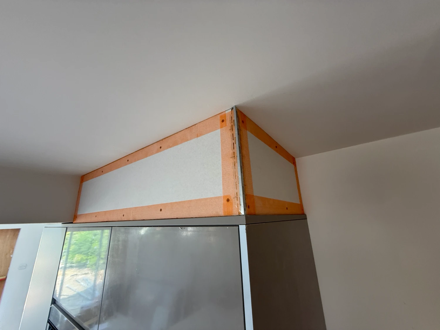 A boxed bulkhead above a glass balustrade, taped at the angles before skimming