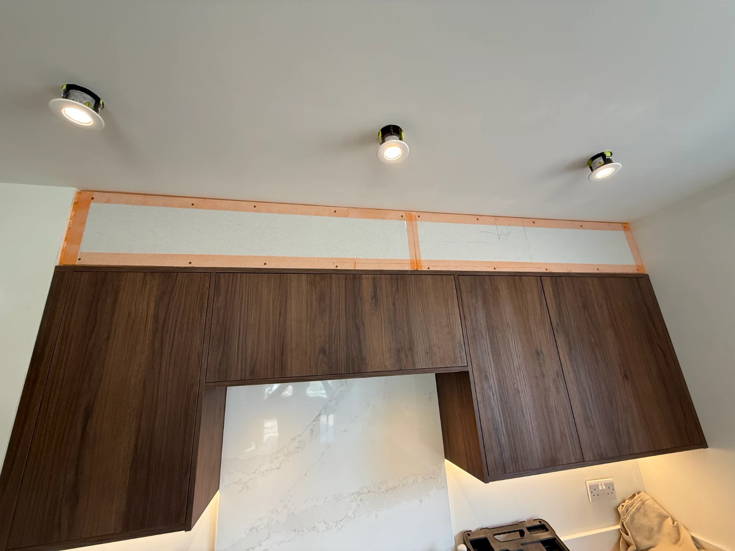 A kitchen bulkhead above the wall units, boarded and taped at the joints before skimming