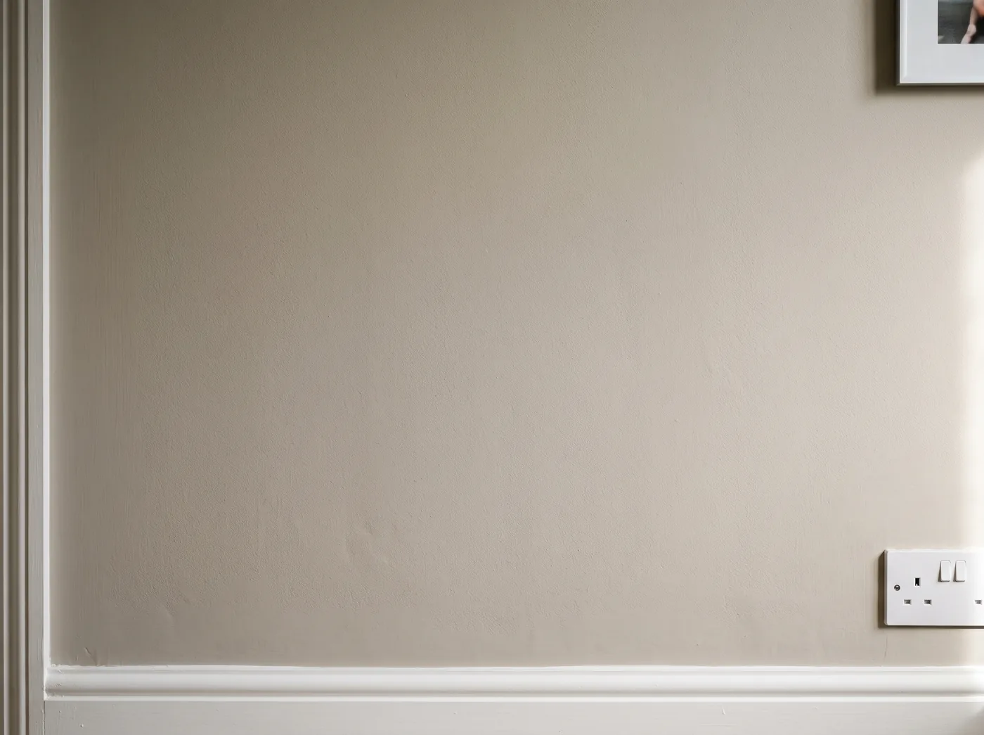 A flat painted wall above the skirting, years after the plaster went on