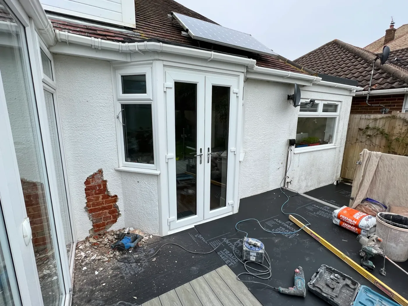The back of a house with the old render taken off and the brickwork showing, ready for a new coat