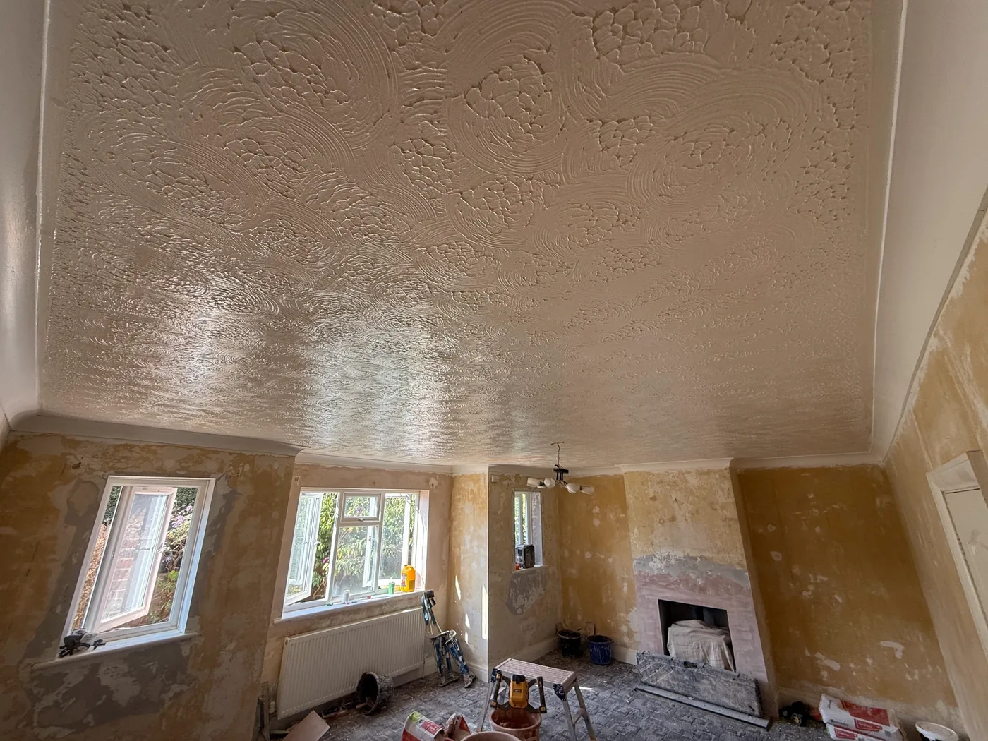 A swirled Artex ceiling over a stripped living room