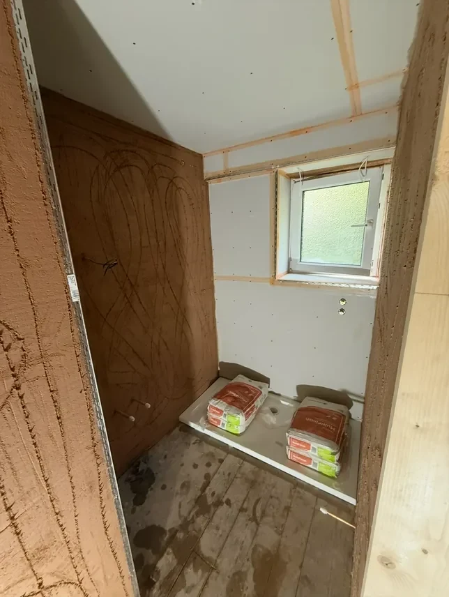A small bathroom boarded out before plastering, with the studwork showing and the boards still bare